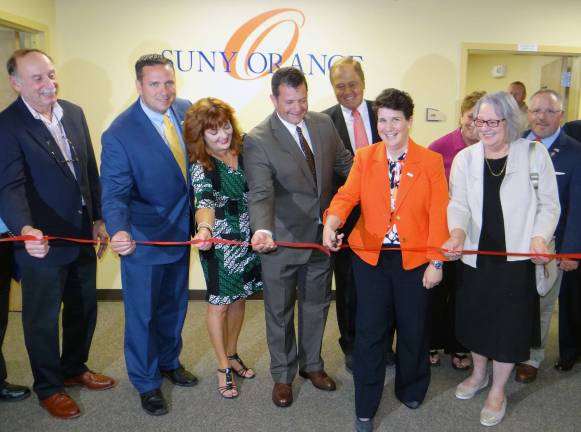 SUNY Orange President Dr. Kristine Young, with scissors, cuts the ribbon on the Sarfatti Education Center. Looking on are (from left): Steven Sarfatti, building owner; Steve Neuhaus, Orange County Executive; Annie Rabbitt, Orange County Clerk; Kelly Decker, Port Jervis Mayor; John Bonacic, New York State Senator; Flo Hannes; newly appointed SUNY Orange Trustee; Helen Ullrich, SUNY Orange Board of Trustees chair; and Tom Faggione, Orange County Legislator representing Port Jervis. (Photo provided)