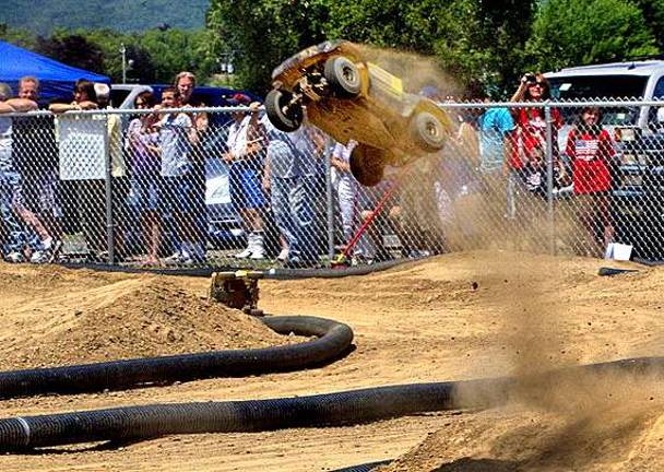 Spectators watch as a racer sails high into the air during a jump during the opening day races at Airport Park's new radio controlled race car track