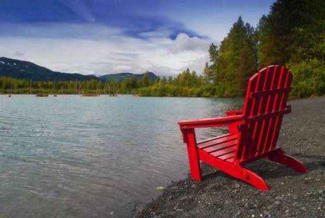 Red Adirondak chair along lakeshore, Alaska