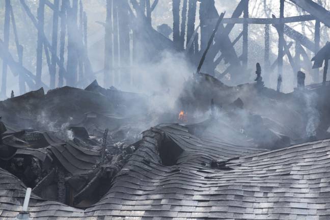 Hot spots still smolder on the roof of the townhouse as the major part of the fire is brought under control (Photo by Robert Breese)
