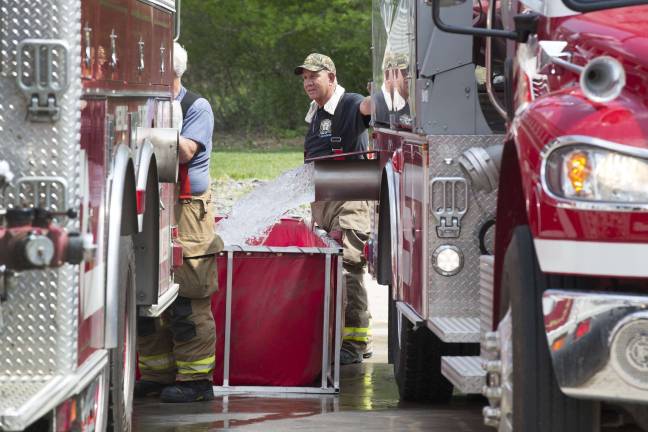 Water is transferred from a fire department tanker to a folding frame water tank in the Walmart parking lot and is used to feed the hose lines fighting the townhouse fire (Photo by Robert Breese)