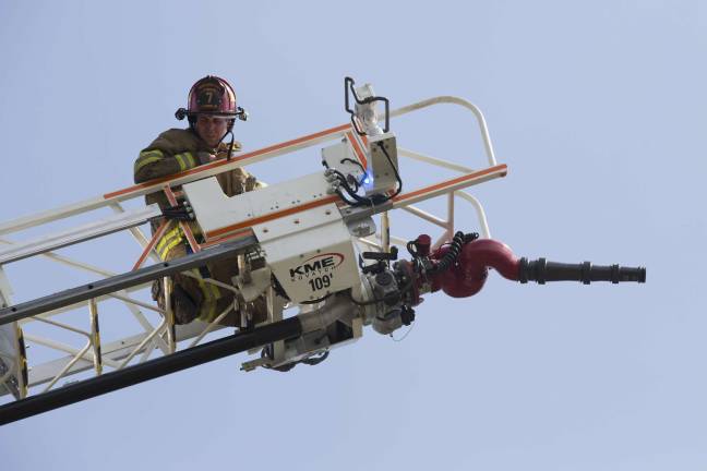 A ladder company firefighter waits for instructions from the ground while setting up at the townhouse fire (Photo by Robert Breese)