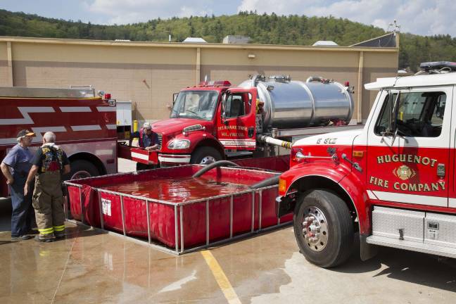 Water brought in by fire dept tankers is transferred to this folding water tank at the Walmart Shopping Center and then pumped back out to the fire hoses (Photo by Robert Breese)