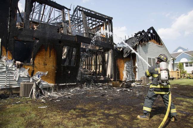 A firefighter places water on the rear wall, ready to collapse, at a burned-out townhouse on Grey Cliff Court in Matamoras (Photo by Robert Breese)