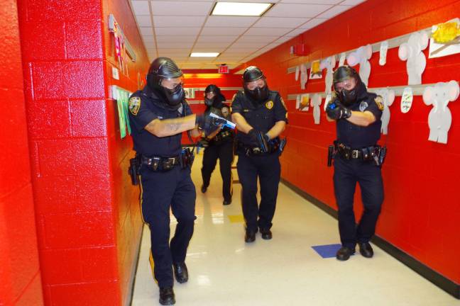 Photo by Chris Wyman With weapons drawn, four Vernon, N.J., Township police officers walk down the main hall at Walnut Ridge Primary School during a practice drill this past August searching for active shooters and hostages.