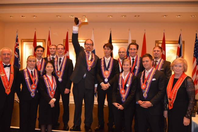 Surrounded by the other competitors, 2012 Best Young Sommelier of the Year gold medal winner Christopher Bates proudly lifts his trophy. At the far left is Klaus Tritschler, Chairman of the competition, Bailli D&#xe9;l&#xe9;gu&#xe9; of Germany, and a member of the International Cha&#xee;ne&#x2019;s Conseil d'Administration. At the far right is Marie Jones, International Vice President, who presided over the awards ceremonies.