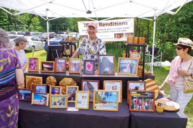 Pennsylvania artist Rick Reis smiles from behind his booth filled with wood-themed art that he and his wife, Deb, created. The couple owns Reis Renditions.