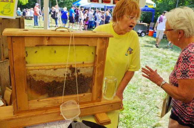 Standing behind a hive Dingmans Ferry beekeeper Suzanne Theobald speaks with a guest. Theobald owns A Touch for Health, which sells raw honey and organic teas.