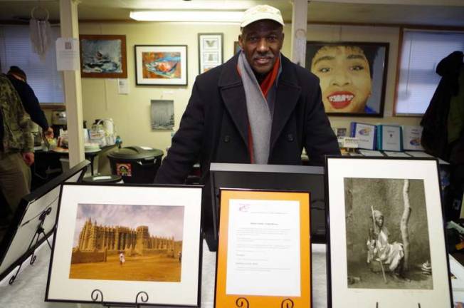 Photographer Teddy Wilson with two photographs he took while traveling in Africa. He has shown his work professionally since 1968, and his work has been displayed throughout the United States. (Photo by George Leroy Hunter)