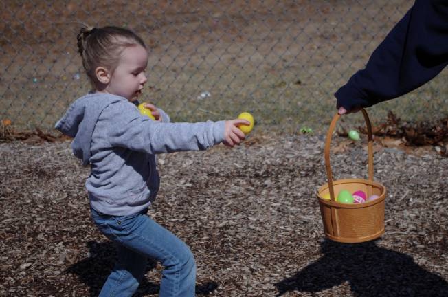 Three year old Kira Sanders of Dingmans Ferry carries an arm load of Easter eggs to a waiting basket.