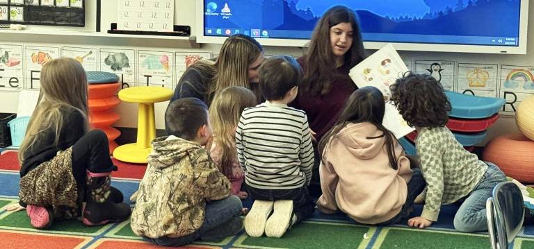Delaware Valley High School freshmen Megan Sohn (left) and Alexcia Ramondino reading with elementary students. As part of the National Read Across America program, the United Way donated a book for every kindergarten student.
