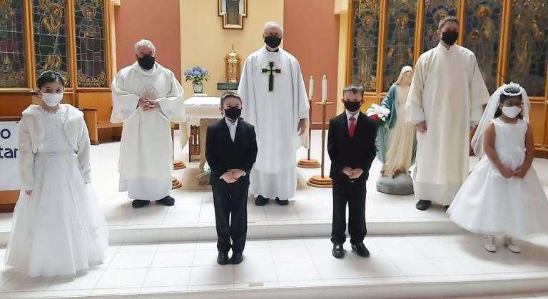 First Communion students pose with Father Joseph Manarchuck, Pastor, and Deacons Mike Calafiore, and Tom Spataro