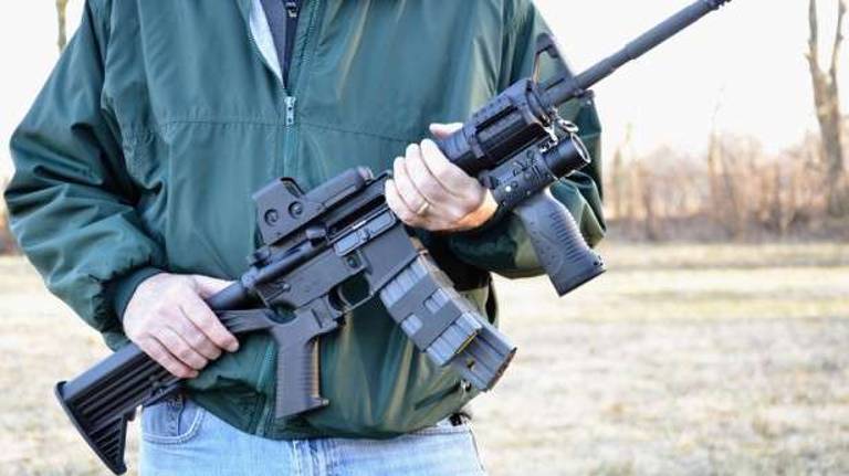 Man holding a Colt AR-15 A3 Tactical Carbine assault weapon.