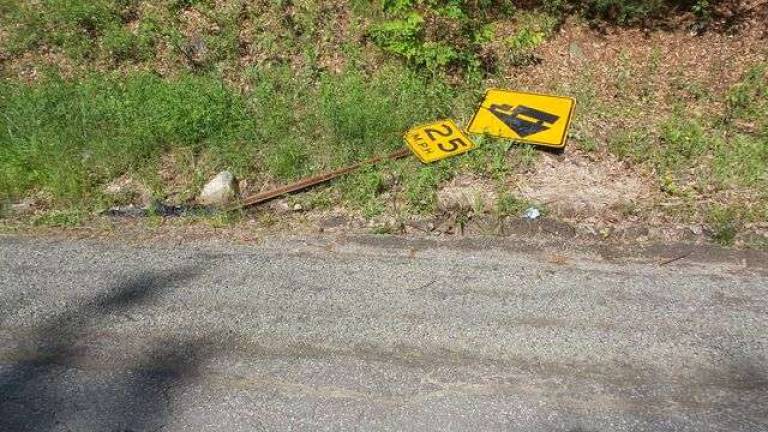 An important road sign lays on the ground near potholes and detritus (Photo by Frances Ruth Harris)