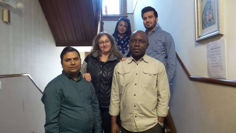 Standing in front: Om Timsina, case manager; Sonya Sarner, Refugee Immigration Services program director; and Marc Ngongo, case manager. In the rear are case managers Maggy Makary and Nasir Abdul Quddus (Absent: case worker Ram Timsina) (Photo by Frances Ruth Harris)